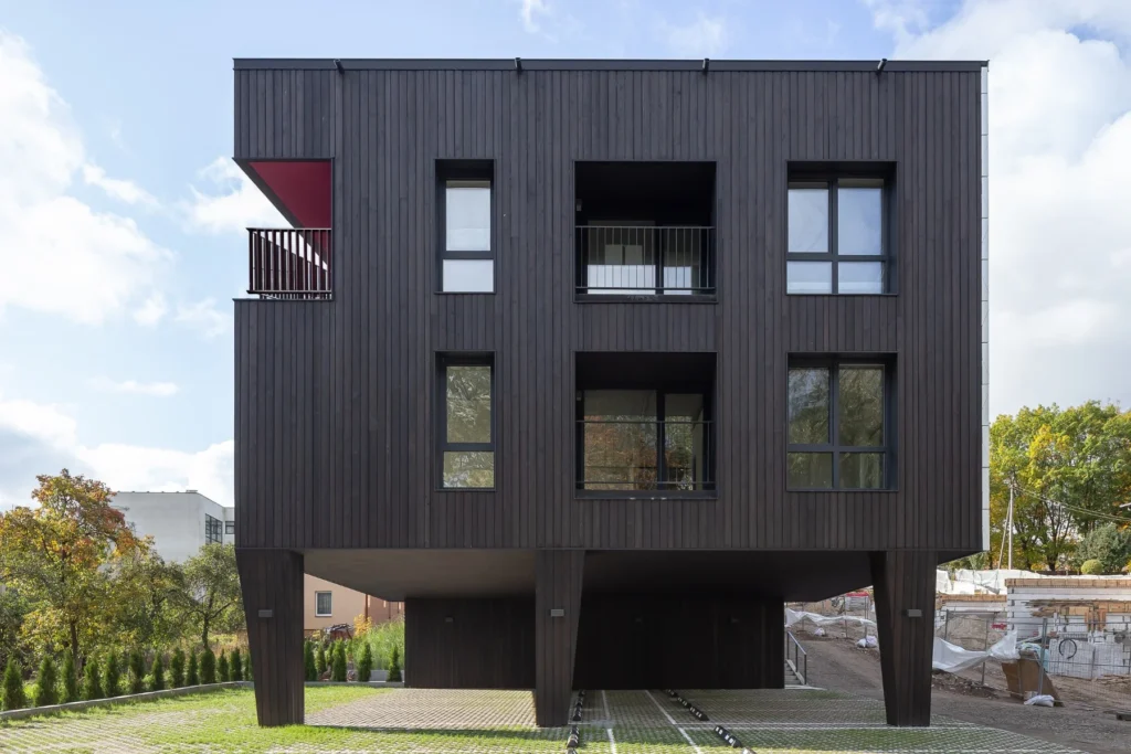 Edificio moderno con fachada de madera Yakisugi (Shou Sugi Ban) en color negro carbonizado, diseño minimalista y elevado sobre pilotes.